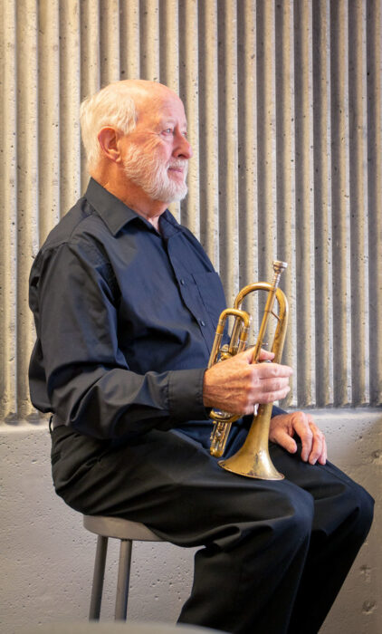 Bob Thurman holding the cornet near a sunny window overlooking downtown Springfield