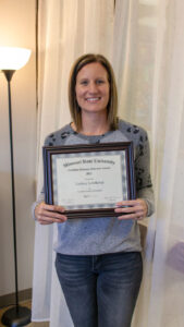 Ms. Lindsey smiling and holding an award