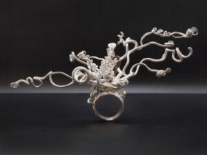 A silver ring with various abstracted white vines coming from it.