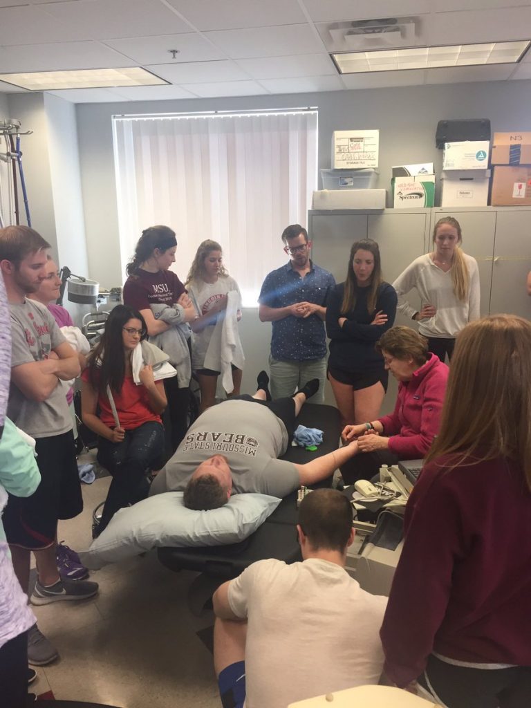Students watching faculty instruction with patient
