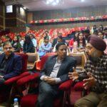 Dr. Kartik Ghosh speaking with a colleague in large auditorium seating