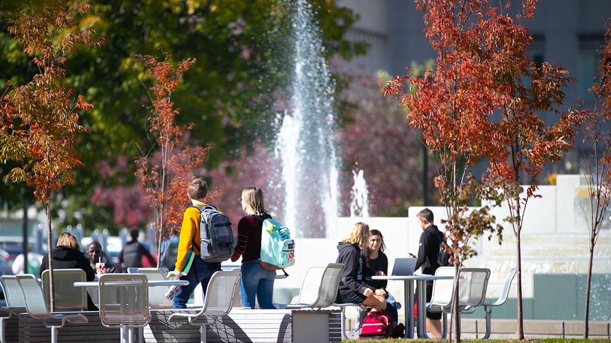 Students walk past fountain on fall day