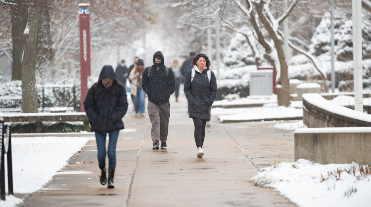 Masked students on snowy walkway.