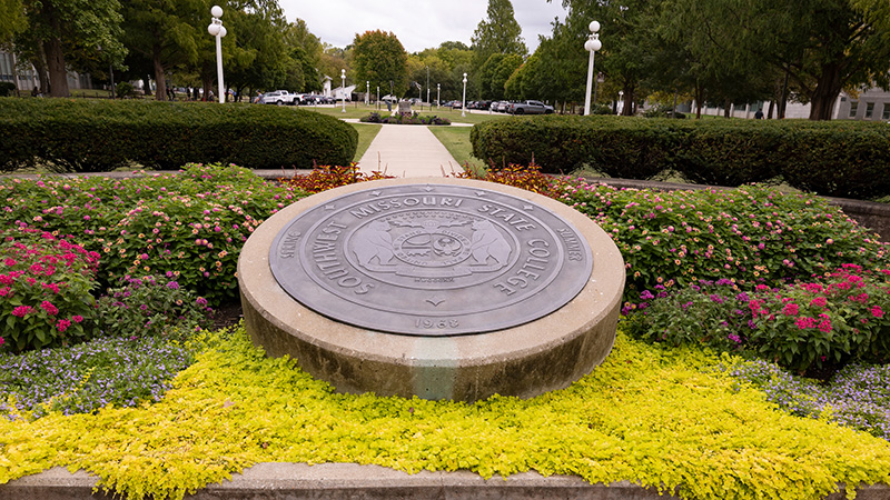 The MSU seal surrounded by colorful flowers.
