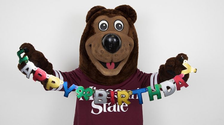 Boomer holds a "Happy Birthday" sign.
