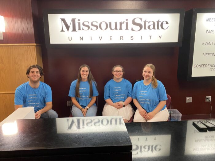 Four School of Accountancy students, smiling while they volunteer at the registration table of the IMA Heartland Council Education Conference