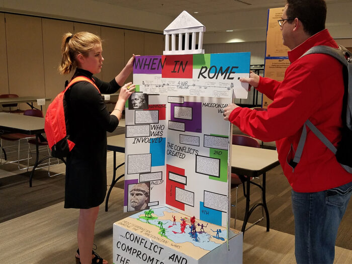Two people setting up a tri-fold presentation board at National History Day