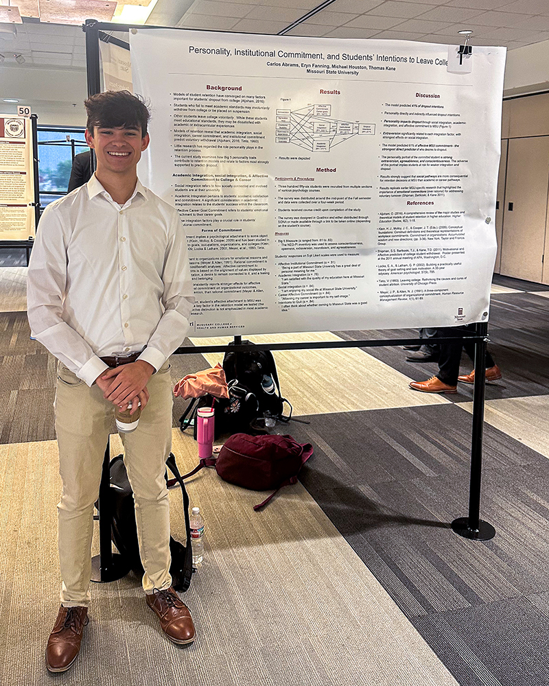 Student standing with his research presentation at the MCHHS Student Research Symposium.