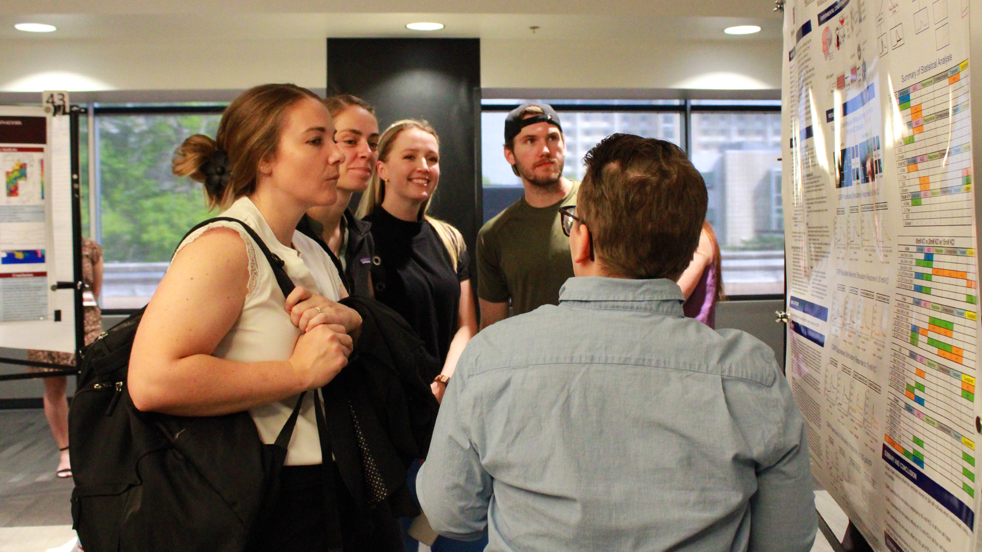 Attendees at the 2025 Einhellig Interdisciplinary Forum discuss a poster presentation with the presenter.