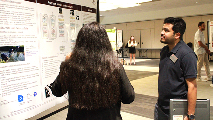 Two people talking about a poster presentation at the Einhellig Interdisciplinary Forum.