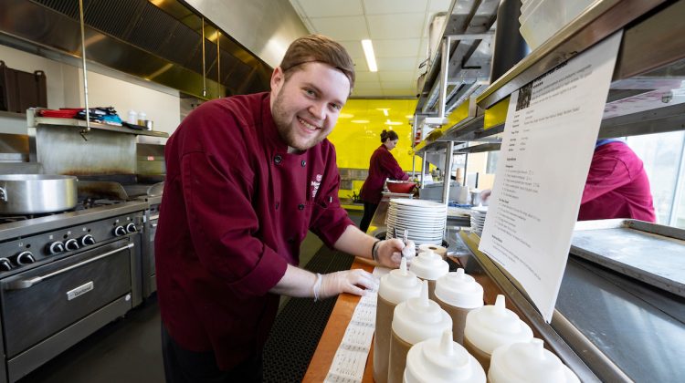 A student chef at Carrie's Cafe, prepping ingredients in the kitchen