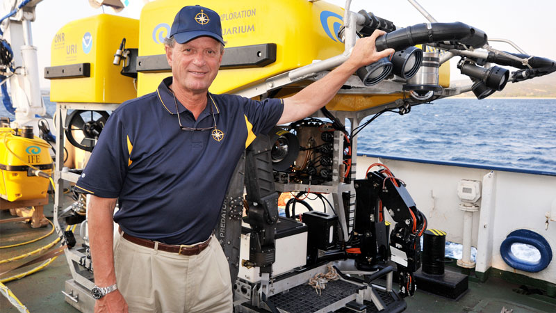 Robert Ballard infront of a yellow ocean exploring machine.