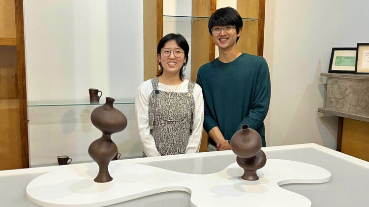 Two individuals pose with artwork