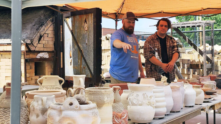 Two individuals view ceramics artwork