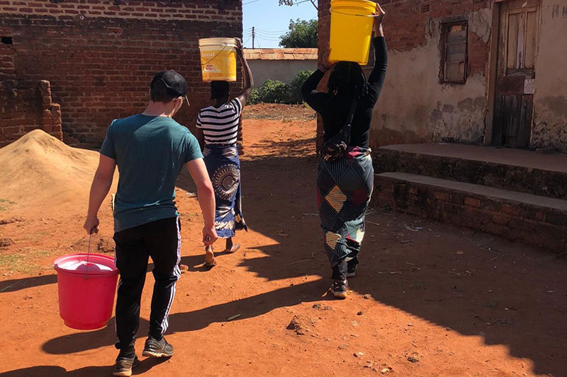 Three individuals carrying water