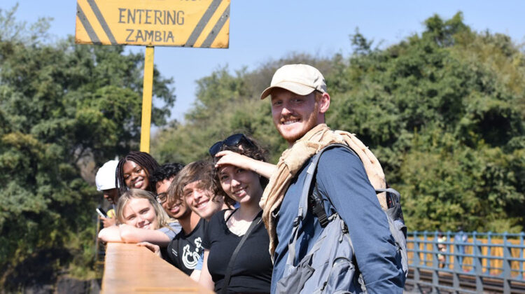 Six students on bridge pose for camera