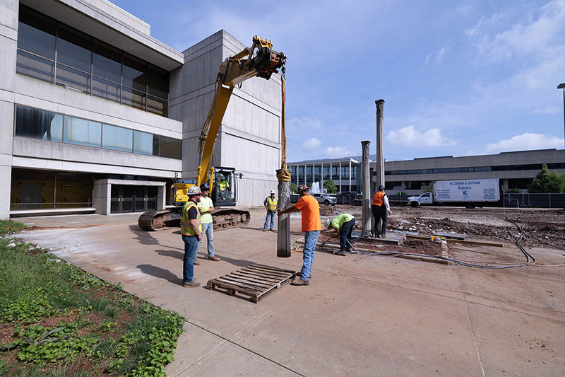 Five construction workers removing sculpture