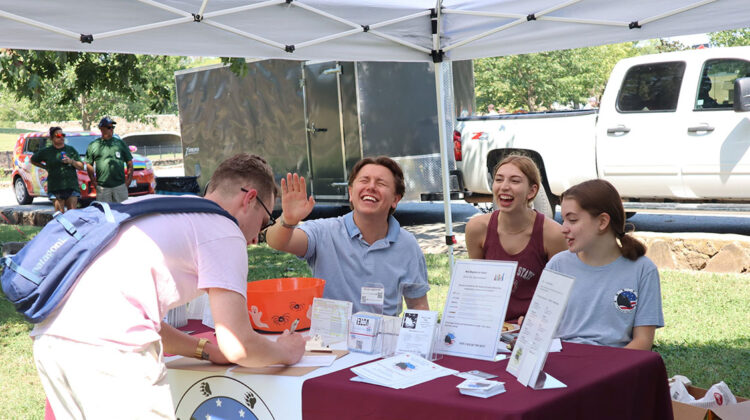 Four individuals laughing outside at registration tent