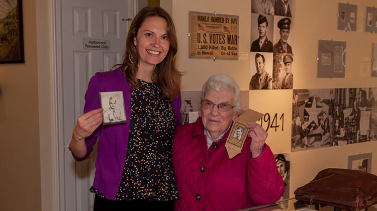Two women smiling for camera while holding war memorabilia