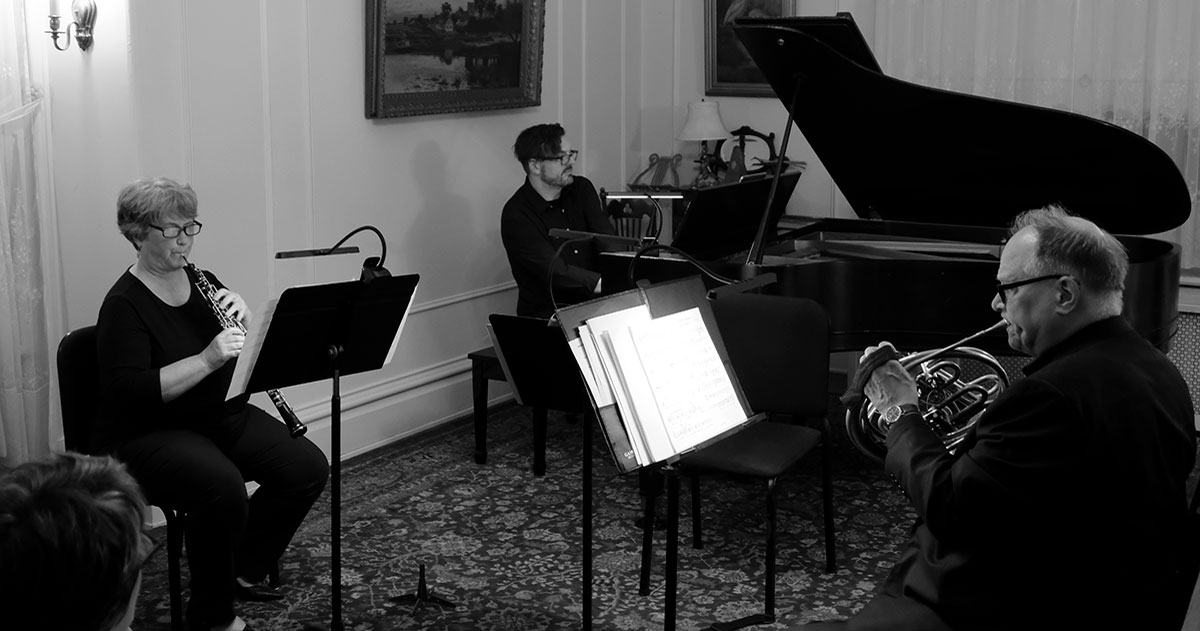 Three musicians playing oboe, piano, and cello