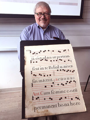 Man smiling holding large copy of music
