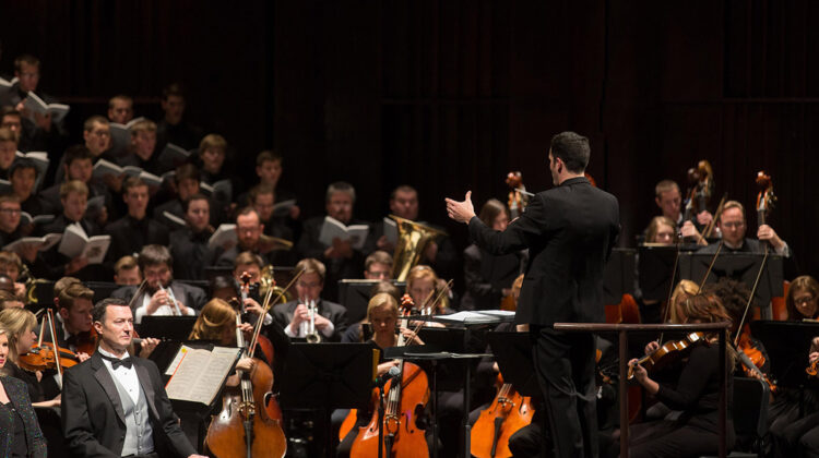 Man conducts orchestra and choral groups