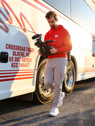 Austin Wood walks with camcorder outside team bus