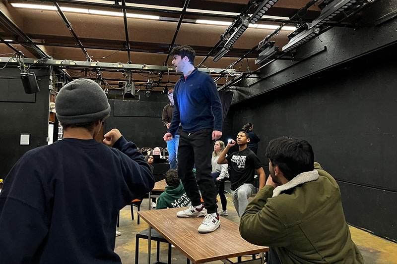Young actor standing on table surrounded by others