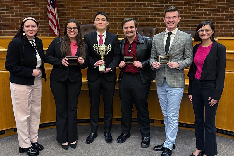 Six students posing with trophy