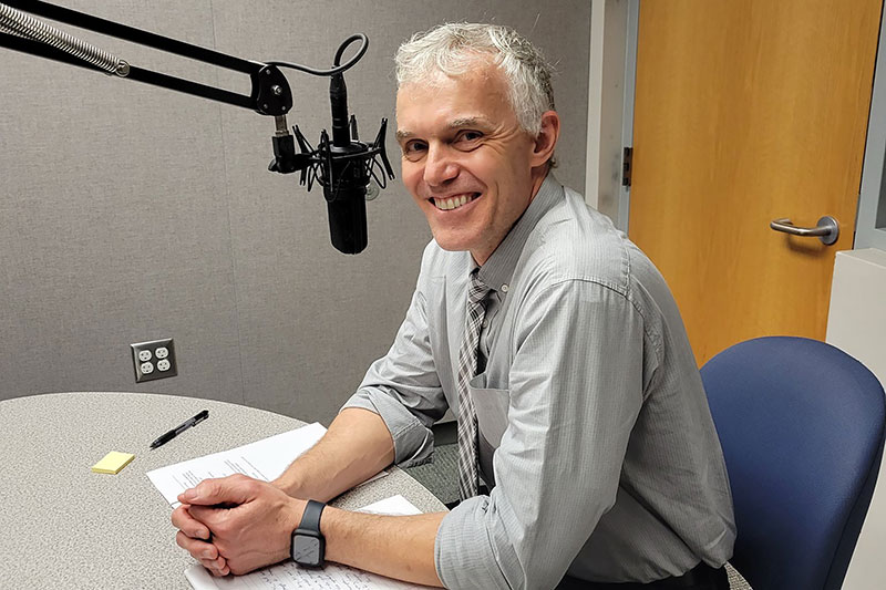 Man sitting at table in front of microphone.