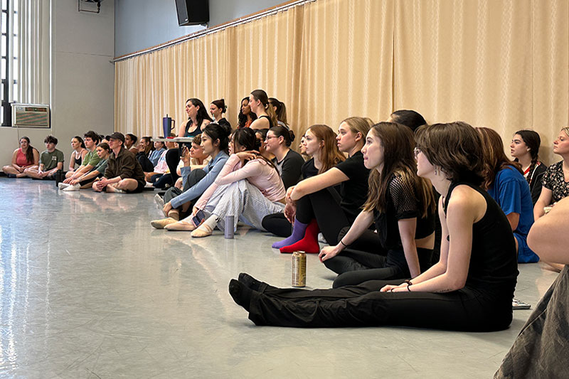 Crowd of young people sitting on floor watching performance