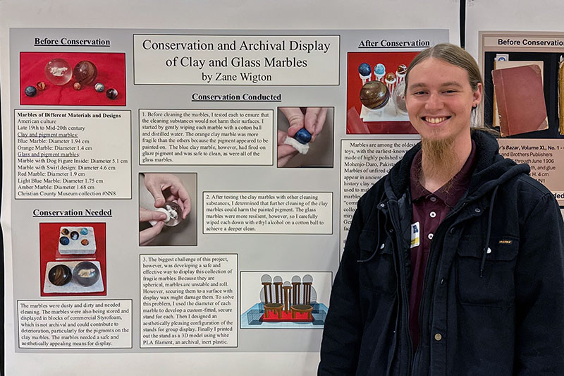 Young man stands next to research presentation poster