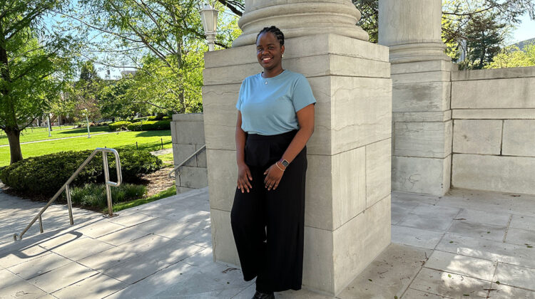 Students stands against pillar of academic hall