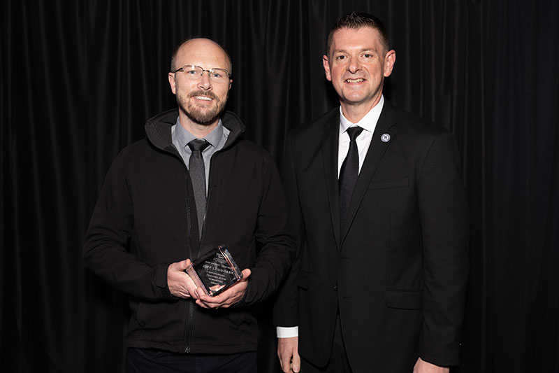 Two men with one holding an award