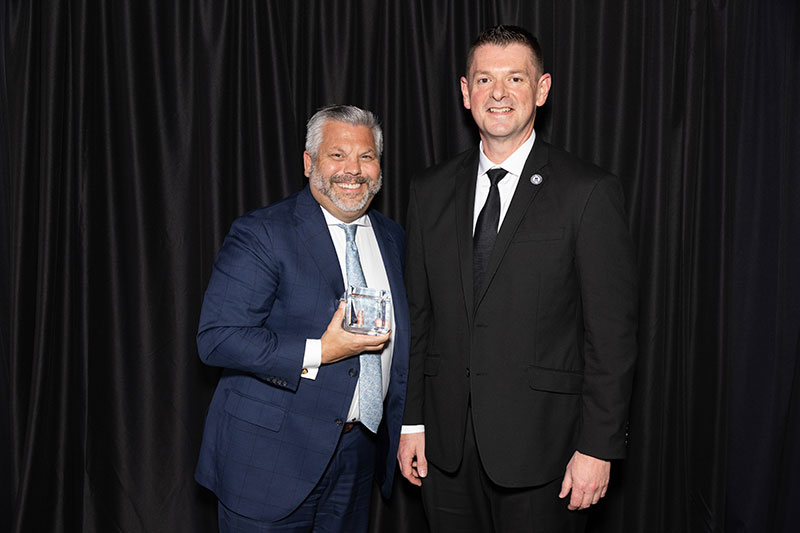Two men with one man holding an award