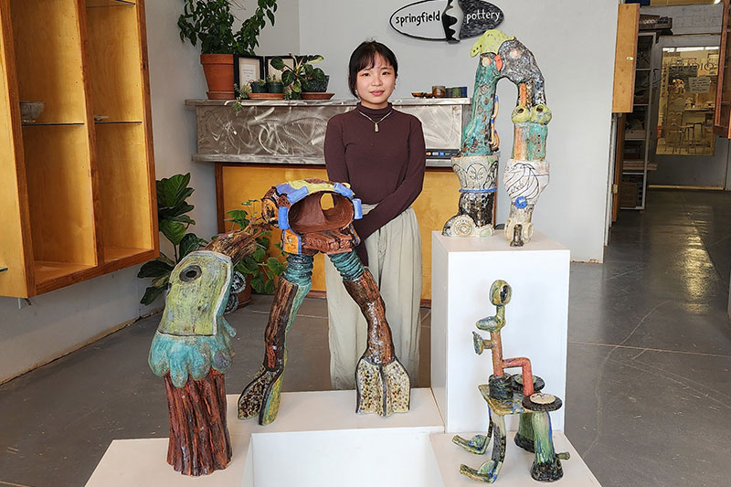 Young woman standing next to ceramic artwork display.