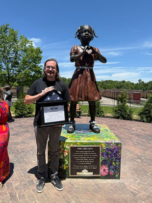 Man holding award and standing next to statue