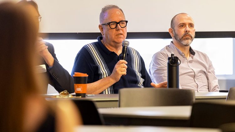 Man sitting at discussion table speaking into microphone