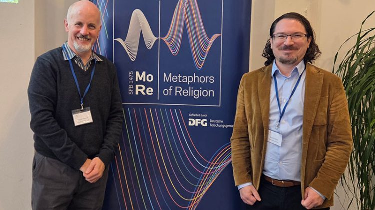 Two men standing in front of a conference poster