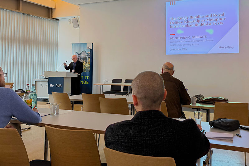 Man standing at podium giving a presentation to audience members