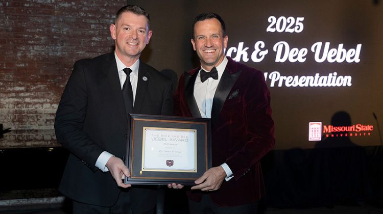 Dean Shawn Wahl accepts award plaque from Dr. Cameron LaBarr