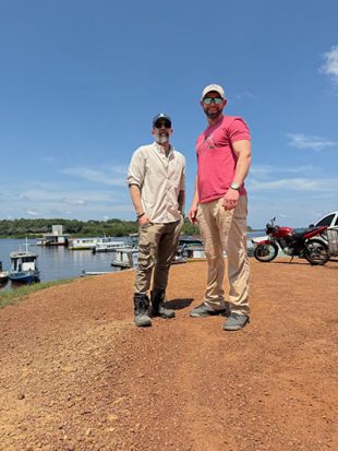 Two men standing outside on a river bank