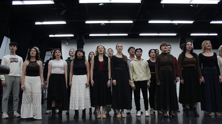 Group of students singing on stage during a rehearsal
