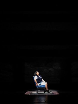 Young woman singing a solo performance on darkened stage
