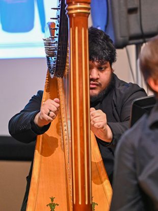 Young man playing a harp in an orchestra