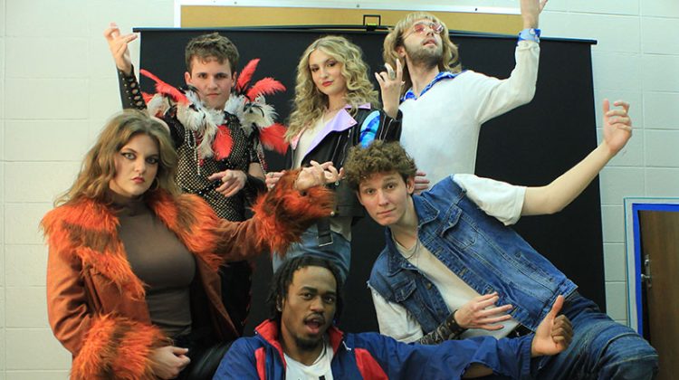 Group of college actors playing air guitar