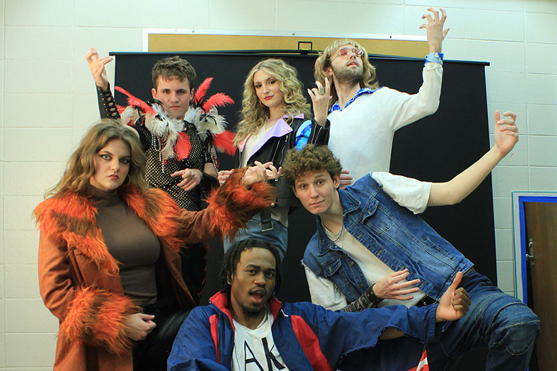 Group of college actors playing air guitar