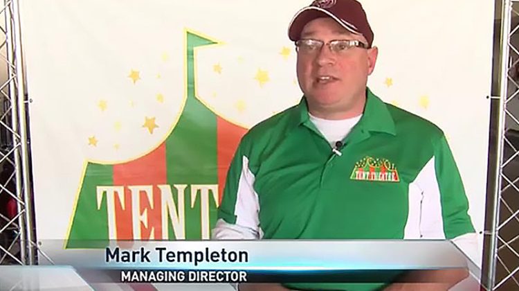 Mark Templeton stands in front of Tent Theatre banner