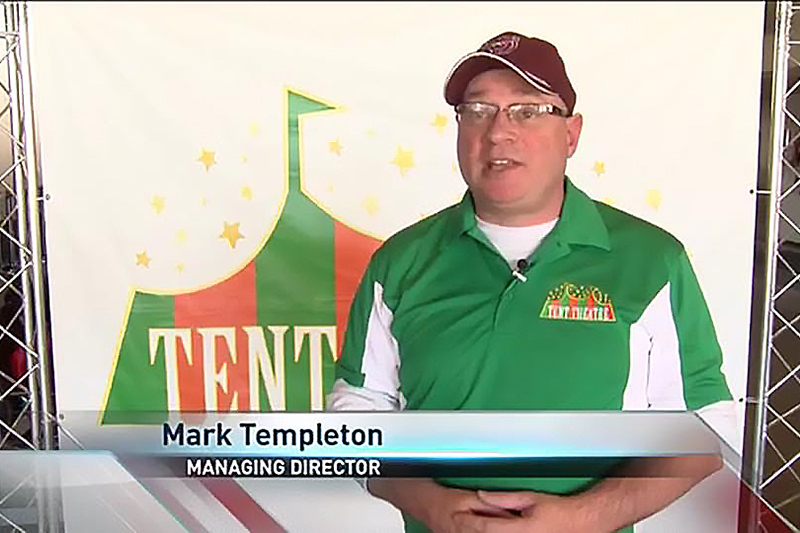 Mark Templeton stands in front of Tent Theatre banner
