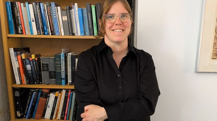 Smiling woman standing in front of book case